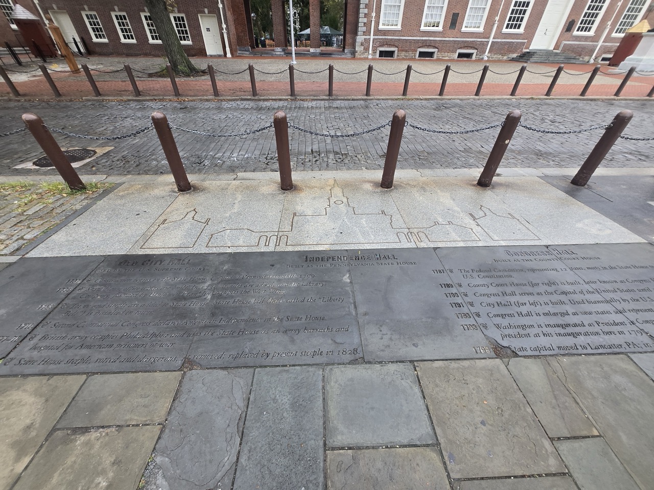 a stone walkway with metal poles and a brick sidewalk