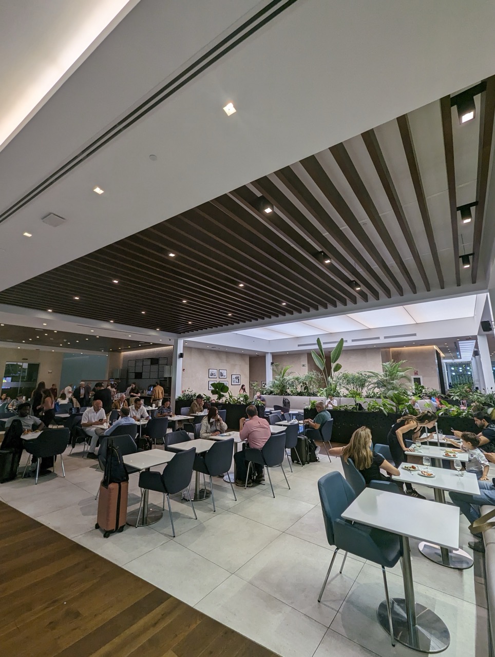 a group of people sitting at tables in a room with plants