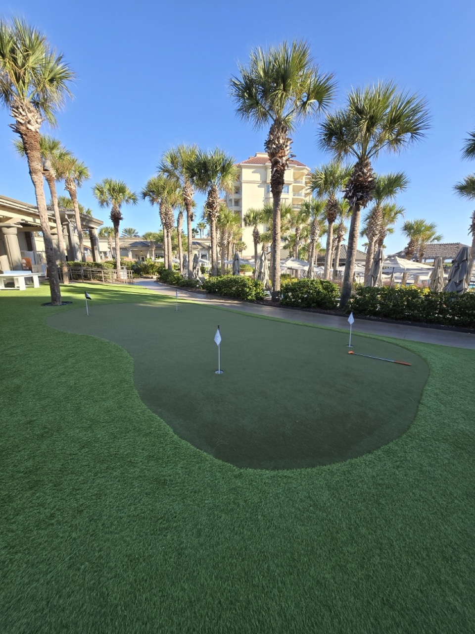 a golf course with palm trees and a building