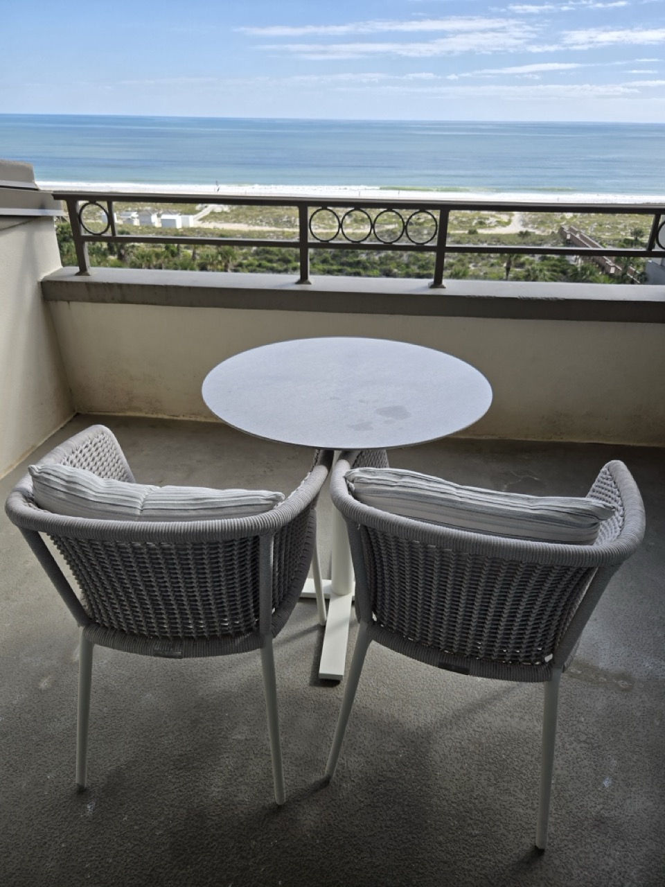 a table and chairs on a balcony overlooking the ocean